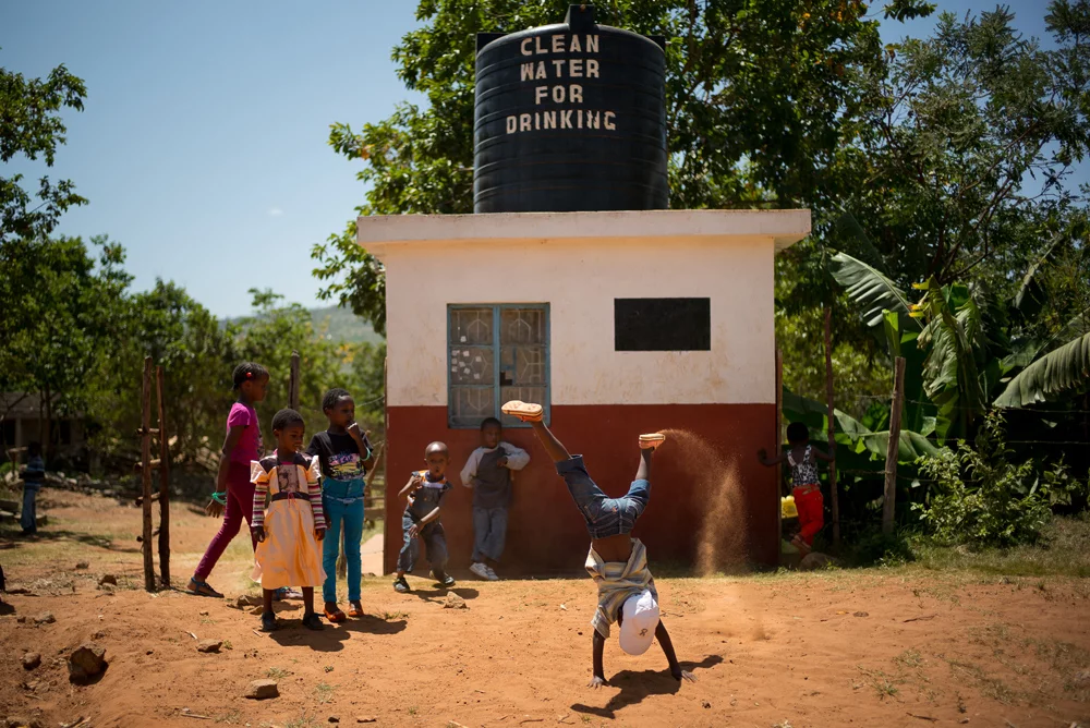 Kids do cartwheels outside of water kiosk in Kenya.