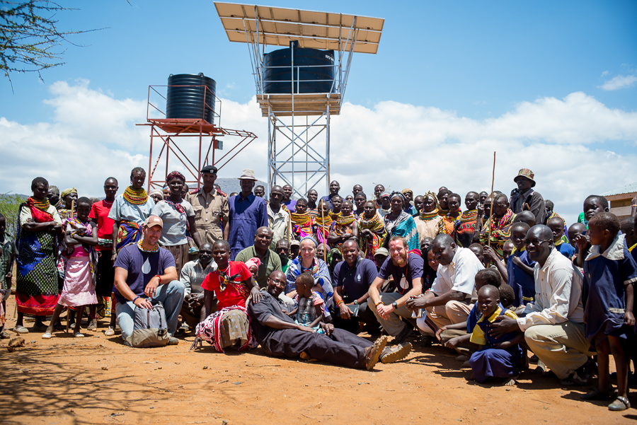 Kenya Community and Team Members Pose Near a Water Tower